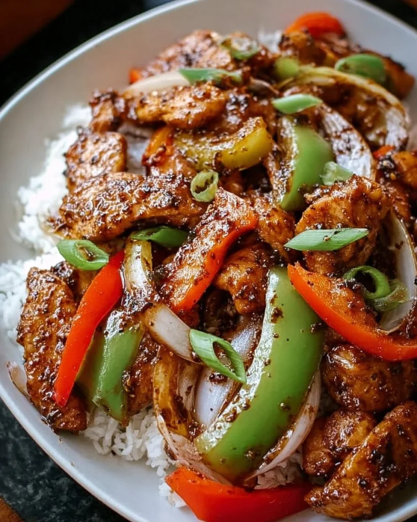 Plate of Black Pepper Chicken garnished with vegetables and herbs