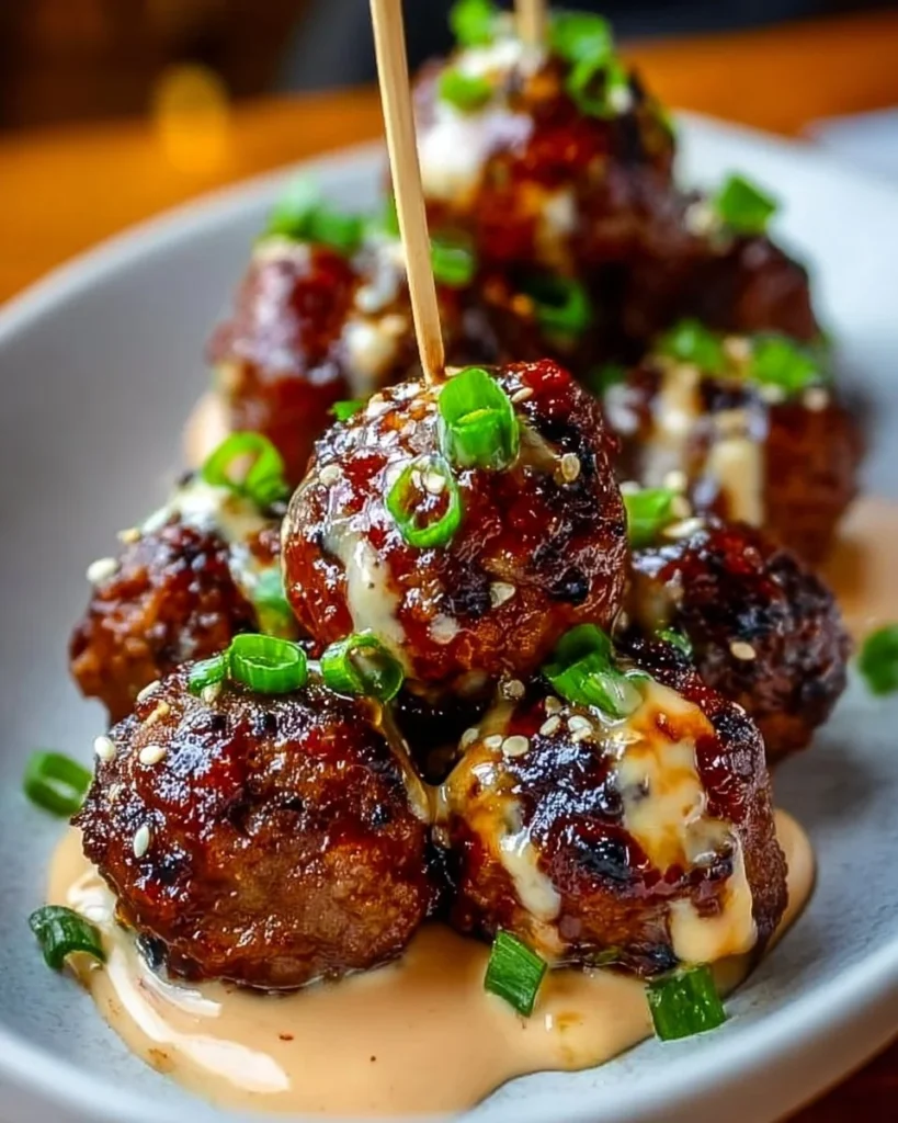 Korean BBQ meatballs with spicy mayo dip on a plate, garnished with green onions.