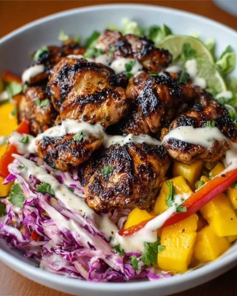 Jerk chicken and mango slaw bowl with honey lime cream on a plate